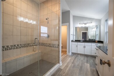 Bathroom featuring hardwood / wood-style flooring, a shower with shower door, and vanity