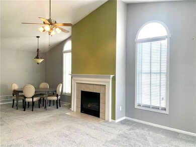 Carpeted living room featuring a fireplace, vaulted ceiling, a healthy amount of sunlight, a high ceiling, and ceiling fan