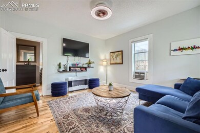 Living room featuring wood finished floors, a textured ceiling, cooling unit, and baseboards