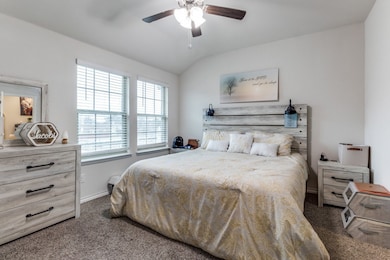 Bedroom featuring dark colored carpet, lofted ceiling, and a ceiling fan