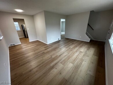Unfurnished living room with light wood-style flooring and stairway