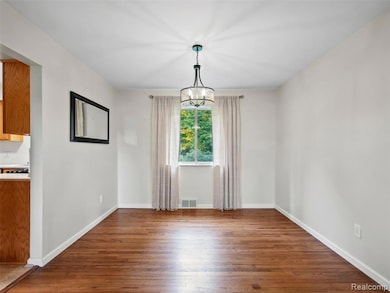 Unfurnished dining area featuring dark wood-style flooring and a chandelier