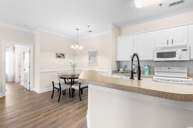 Kitchen featuring white cabinets, white appliances, ornamental molding, light wood-type flooring, and tasteful backsplash