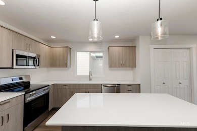 Kitchen featuring appliances with stainless steel finishes, decorative light fixtures, recessed lighting, a kitchen island, and modern cabinets