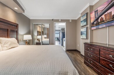 Bedroom with ornamental molding, dark wood finished floors, and a closet