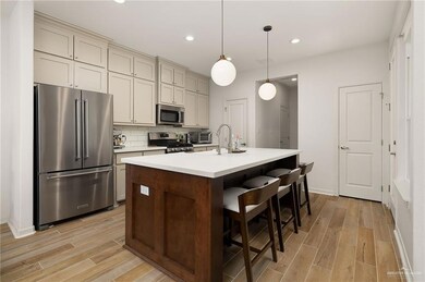 Kitchen featuring stainless steel appliances, light wood-type flooring, light countertops, recessed lighting, and a kitchen bar