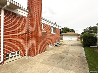 View of home's exterior with a patio area, brick siding, a chimney, a garage, and an outdoor structure