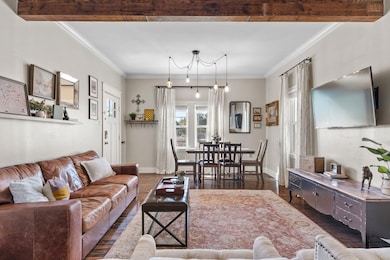 Living area featuring crown molding and dark wood-style floors