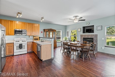 Kitchen featuring light countertops, open floor plan, stainless steel appliances, dark wood finished floors, and a fireplace