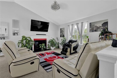 Living room featuring lofted ceiling, a fireplace with flush hearth, and carpet floors