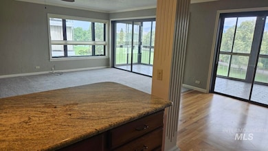 Kitchen with crown molding, light stone countertops, ceiling fan, dark brown cabinetry, and a textured wall