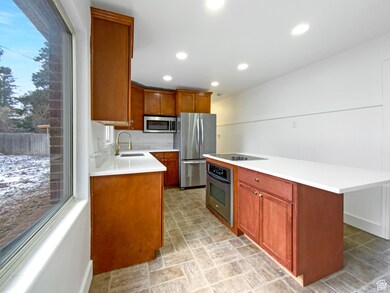 Kitchen featuring a center island, stainless steel appliances, recessed lighting, brown cabinets, and light stone countertops