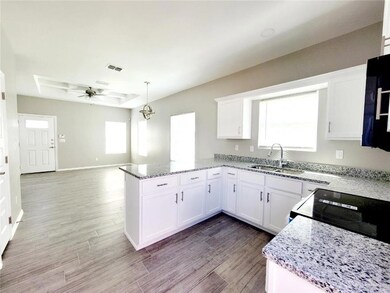 Kitchen with visible vents, a sink, white cabinetry, a peninsula, and a raised ceiling