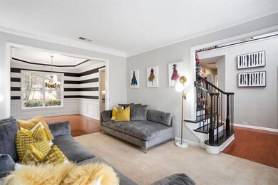 Living area featuring ornamental molding, carpet floors, wood finished floors, a chandelier, and stairway