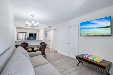 Living room featuring a chandelier, light wood-style flooring, and ornamental molding