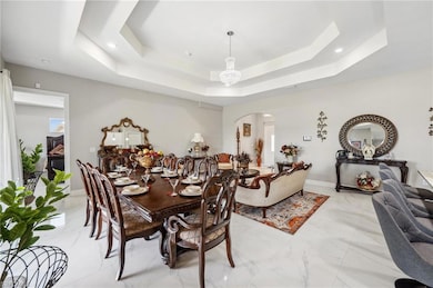 Dining Area with baseboards, a raised ceiling, arc