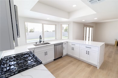 Kitchen featuring dishwasher, a sink, a tray ceili