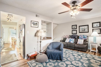 Living area featuring light wood-style floors, ceiling fan, and a textured ceiling
