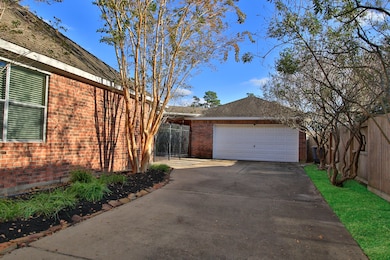 Spacious driveway leading to a two-car garage. A wooden fence adds privacy, and the overall setting is clean and well-maintained.