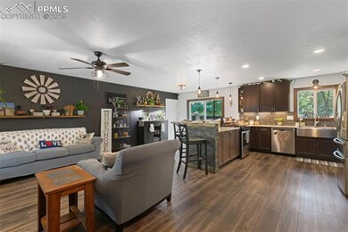 Living area featuring dark wood-style flooring, ceiling fan, and recessed lighting