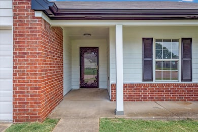 View of exterior entry featuring brick siding and a shingled roof