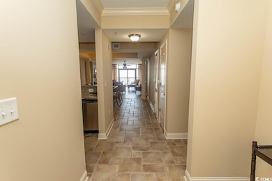 Hall featuring stone tile floors, ornamental molding, and baseboards