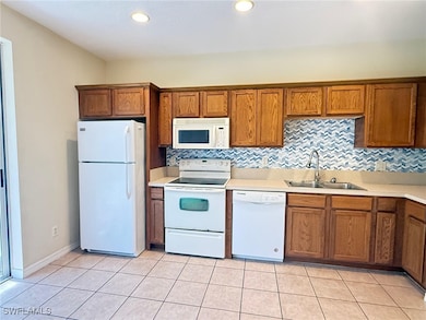 Kitchen with white appliances, a sink, brown cabin