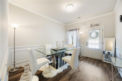Dining room featuring wainscoting, crown molding, dark wood-style floors, and a decorative wall