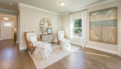 Sitting room with healthy amount of natural light, wood finished floors, and crown molding