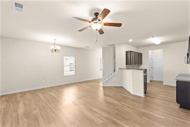 Unfurnished living room with light wood-style floors, ceiling fan, a chandelier, and stairs