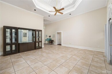 Entryway with light tile flooring, ornamental molding, ceiling fan, and a tray ceiling