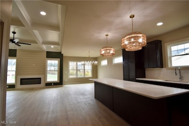 Kitchen featuring hanging light fixtures, coffered ceiling, beamed ceiling, light wood-style floors, and a chandelier