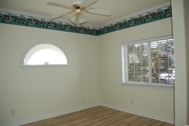 Spare room featuring wood finished floors, Crown molding, plenty of natural light, and ceiling fan