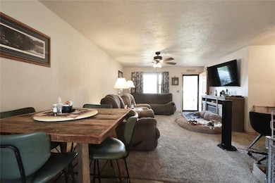 Carpeted dining area with a textured ceiling and a ceiling fan