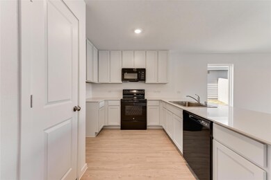 Kitchen featuring black appliances, sink, white ca