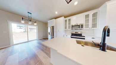 Kitchen featuring hanging light fixtures, light wood-type flooring, white cabinetry, stainless steel appliances, and recessed lighting