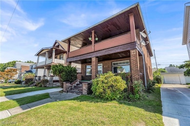 Contemporary home featuring a front yard, a balcony, brick siding, an outbuilding, and a detached garage