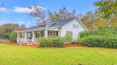 View of front facade featuring covered porch, a front yard, and roof with shingles