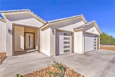 View of front of house featuring stucco siding, concrete driveway, a tiled roof, and a garage