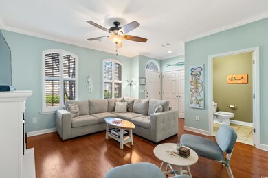 Living room with a ceiling fan, crown molding, dark wood-style floors, and visible vents