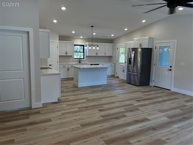 Kitchen featuring recessed lighting, a center island, refrigerator, hanging light fixtures, and white cabinetry