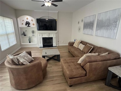 Living room featuring wood finished floors, a fireplace, and ceiling fan