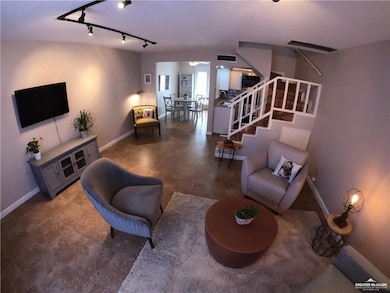 Living area featuring stairs, baseboards, track lighting, and a ceiling fan