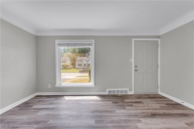 Spare room with a healthy amount of sunlight, hardwood / wood-style flooring, and crown molding