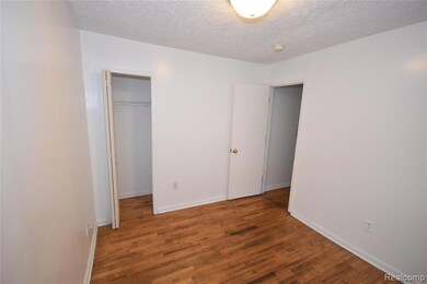 Unfurnished bedroom with wood finished floors, a textured ceiling, and a walk in closet