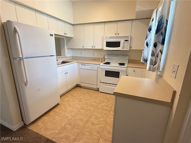 Kitchen with white appliances, light tile patterne