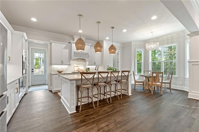 Kitchen featuring dark wood finished floors, healthy amount of natural light, backsplash, a kitchen island with sink, and recessed lighting
