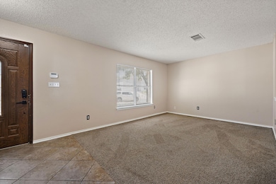 Tiled spare room featuring a textured ceiling and