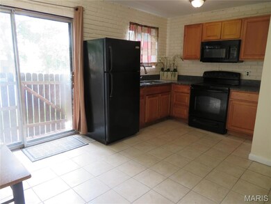Kitchen with black appliances, brown cabinets, light tile patterned flooring, and tasteful backsplash