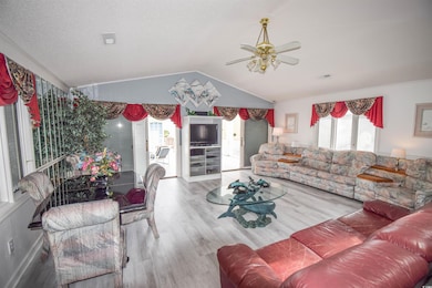 Living room with lofted ceiling, hardwood / wood-style floors, and ceiling fan